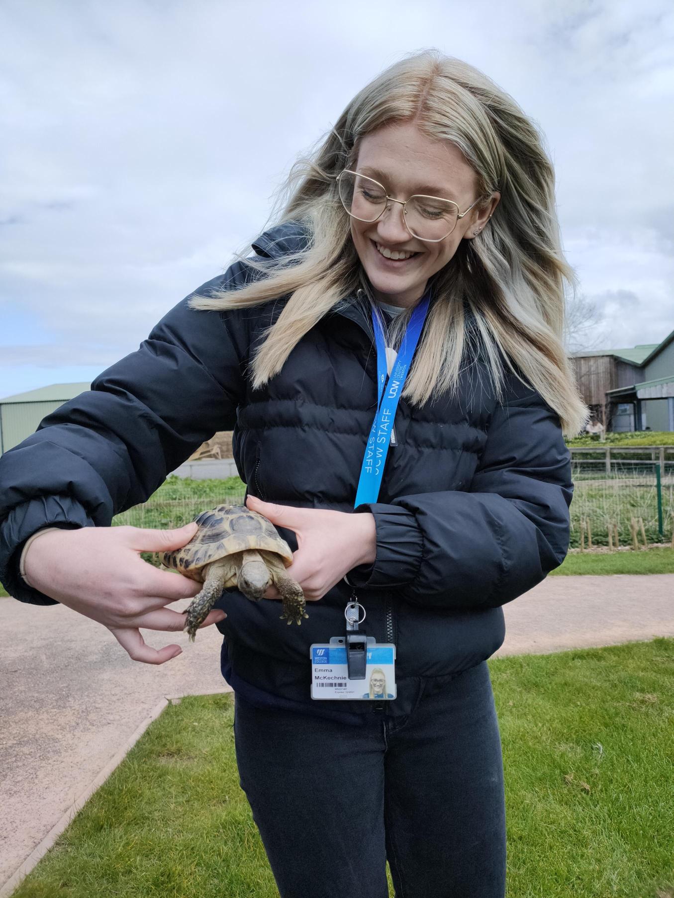 A staff member holding a tortoise.
