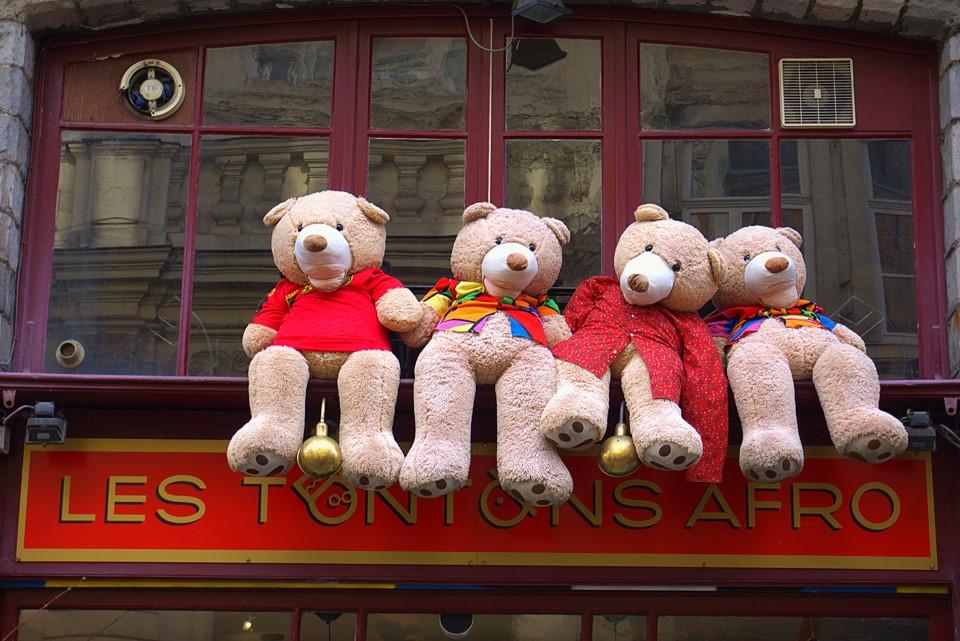 Teddy bears sat on a shop sign in Lille