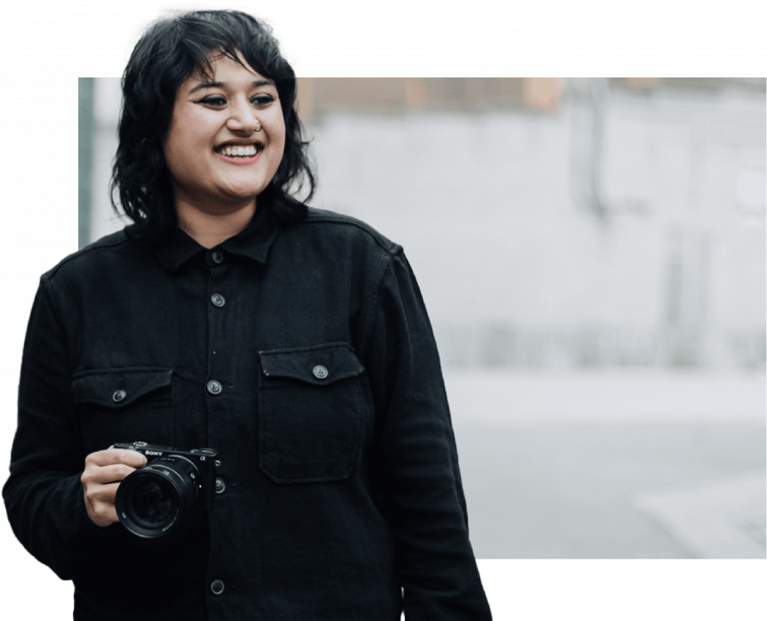 Female media student holding camera with a photoshopped background
