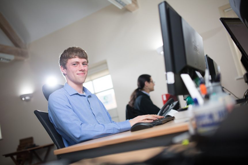 Male Digital and Technology Solution Degree Apprentice working on computer at work