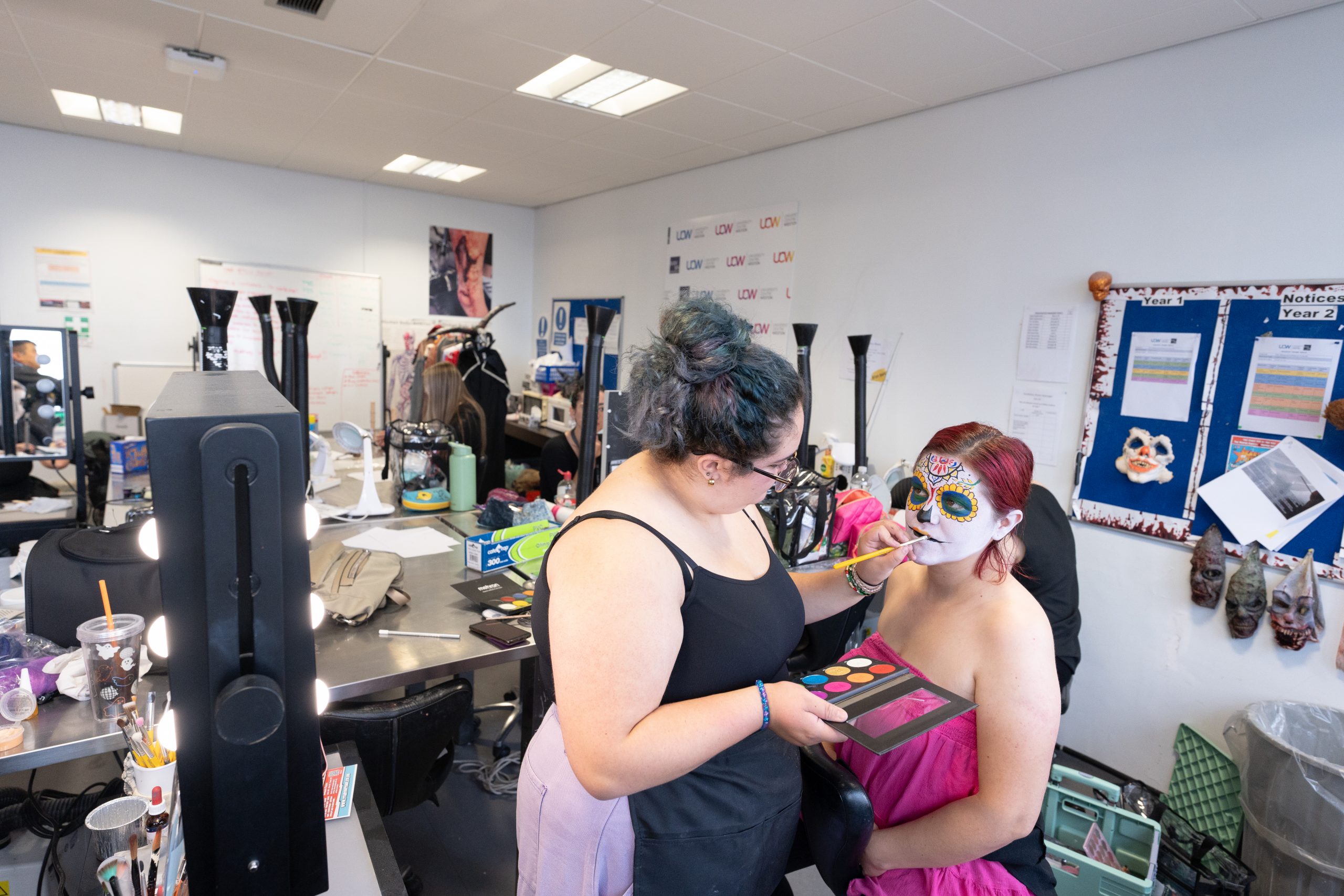 Student applying makeup to a model