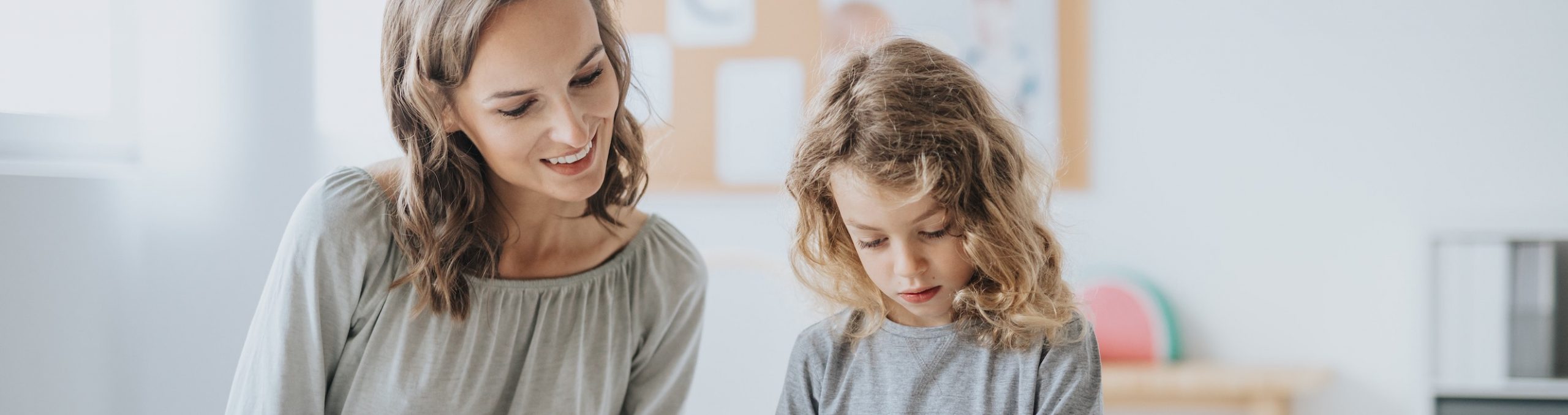 Female Psychologist helping school child express emotions through art with drawing and colouring