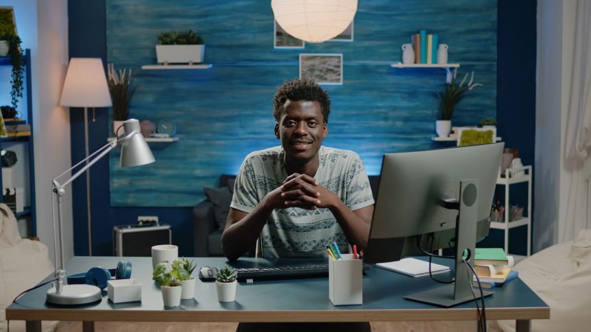 portrait of male computing learner sitting at desk with computer