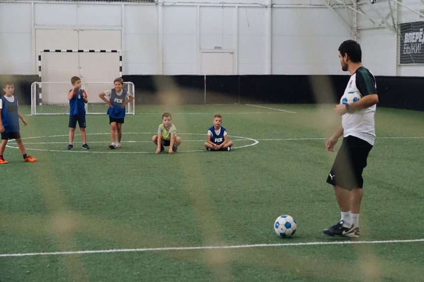 Male sports coach coaching young children