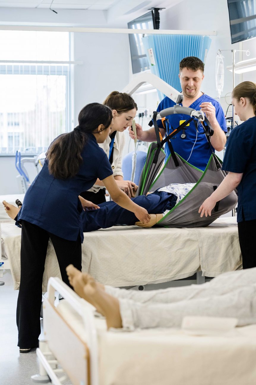 Nursing students working with medical dummy and hoist