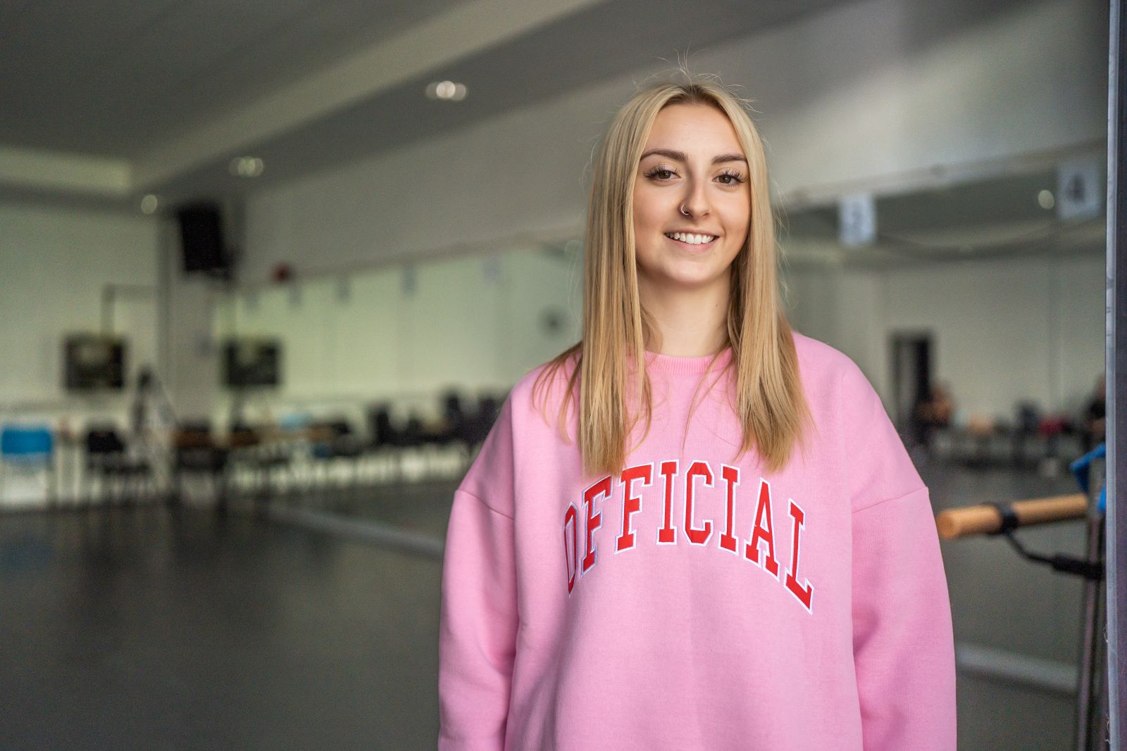 Female Dance student in pink jumpersmiling at the camera