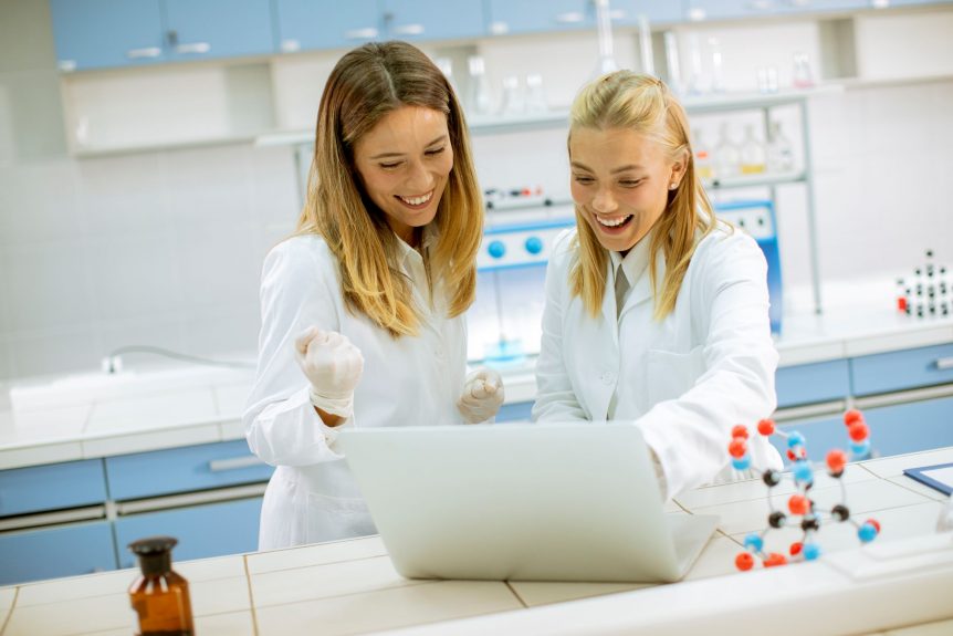 Female students in white lab coats discussing top 10 Bio Lab careers