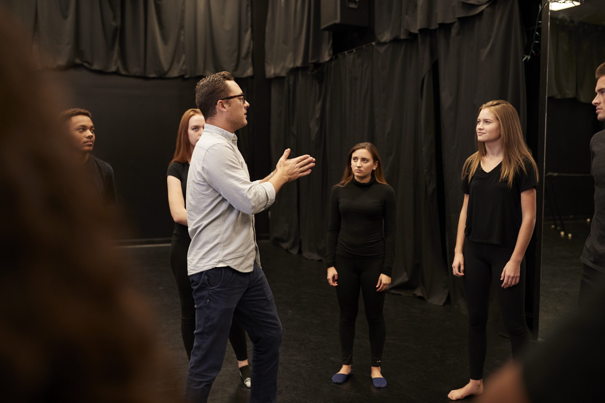 Drama teacher talking to group of acting students