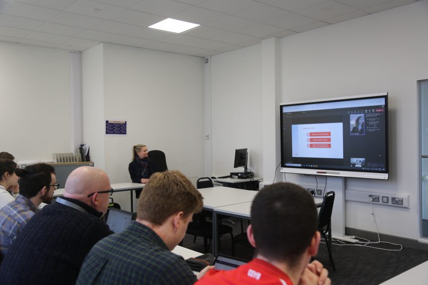 Business students looking at interactive board as virtual guest delivers lecture on teams