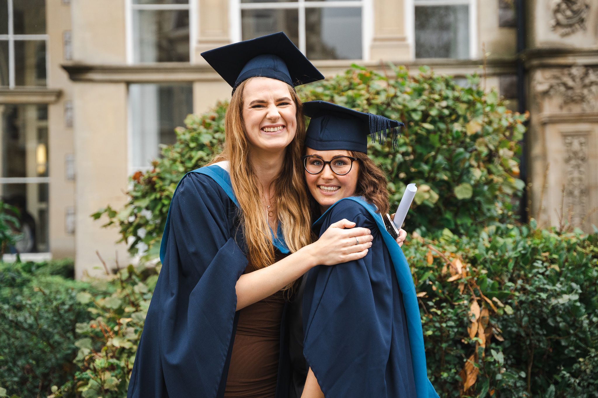 two girls hugging each other with their graduation gowns on