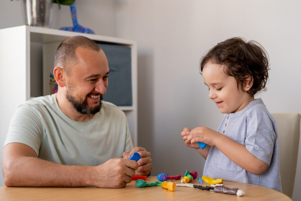 Male teacher playing with blocks with a young boy.
