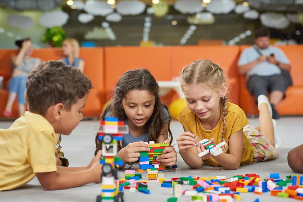 Little boys and girls playing with block toys in playroom.