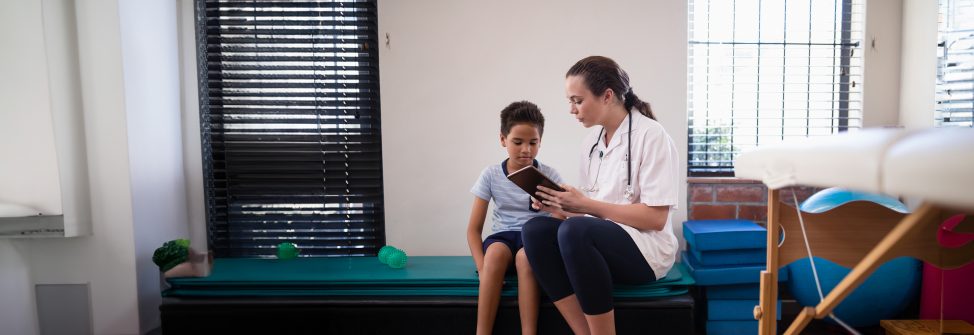 female doctor showing digital tablet to boy