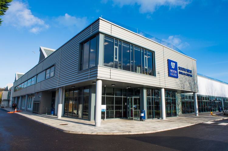 Exterior of Weston College South West Skills Campus building, showing a modern two-storey structure with large windows, metal cladding, and a clear blue sky overhead.