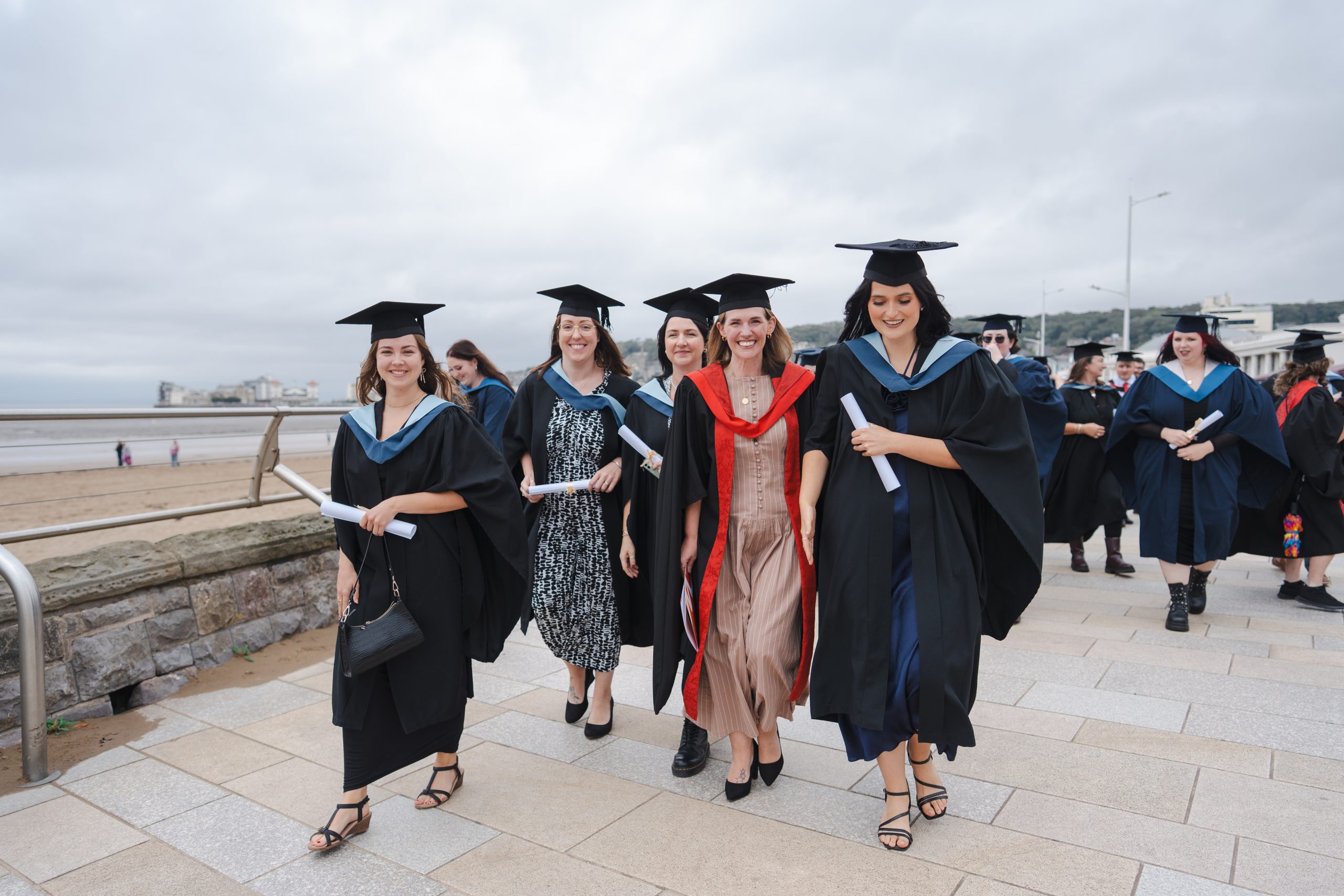 UCW graduates walking along the seafront